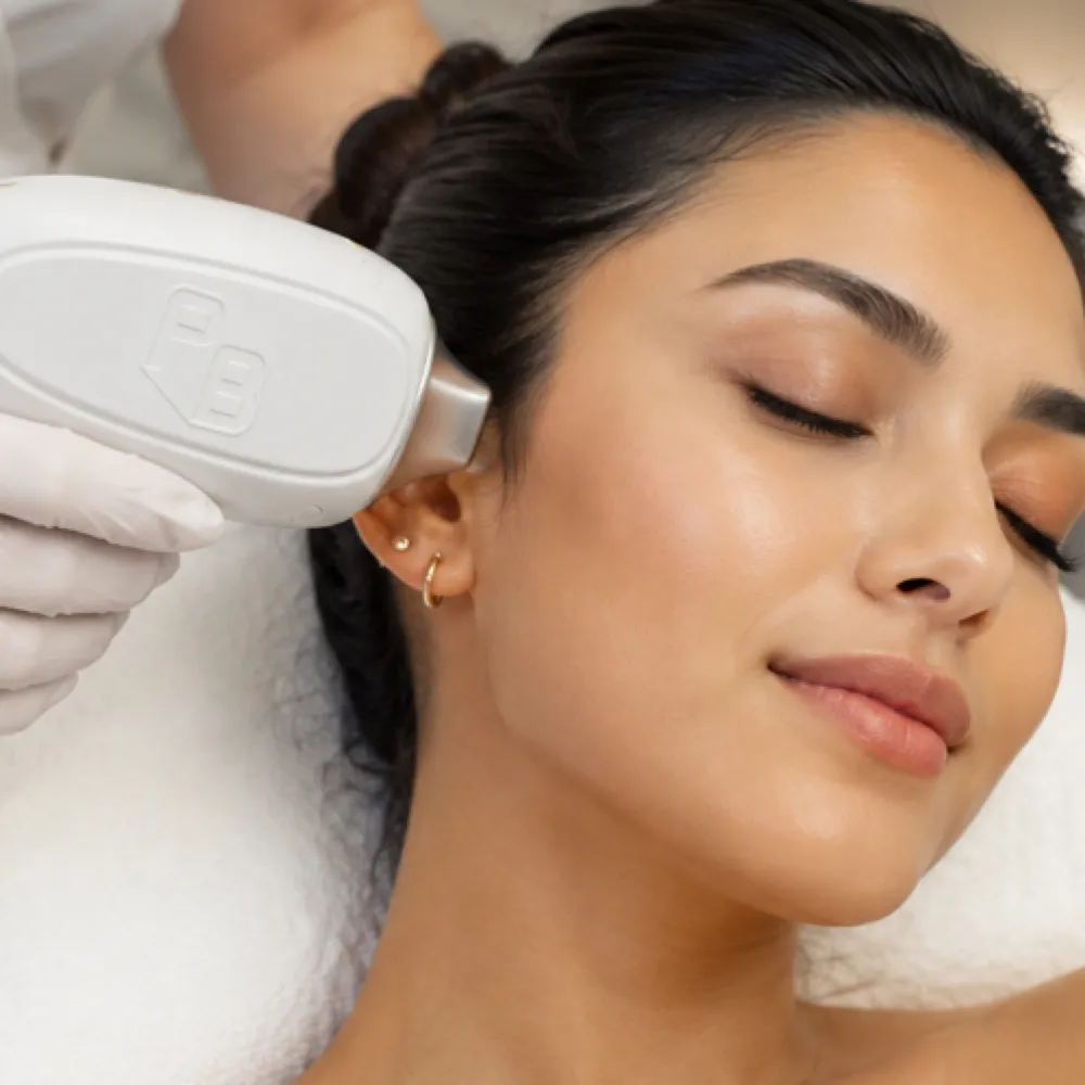 Laser hair removal handpiece held against the side of the face